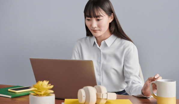 Employee in business clothes sitting at her desk looking at her laptop screen