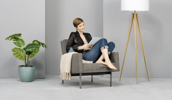 Woman sitting comfortably in a stylish chair barefoot reading a book