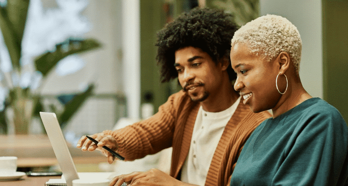 Two people in an office looking at a laptop screen.