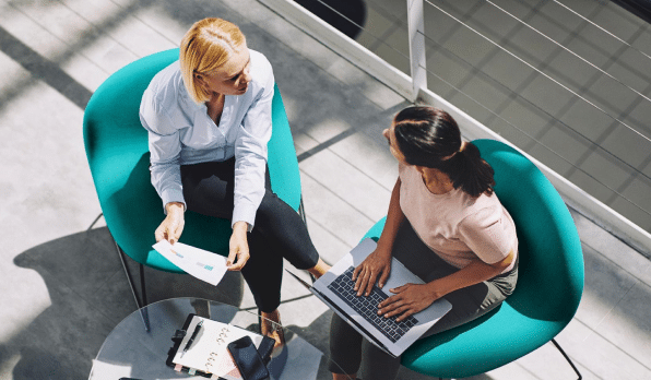 overhead shot of two female employees in business clothes discussing work