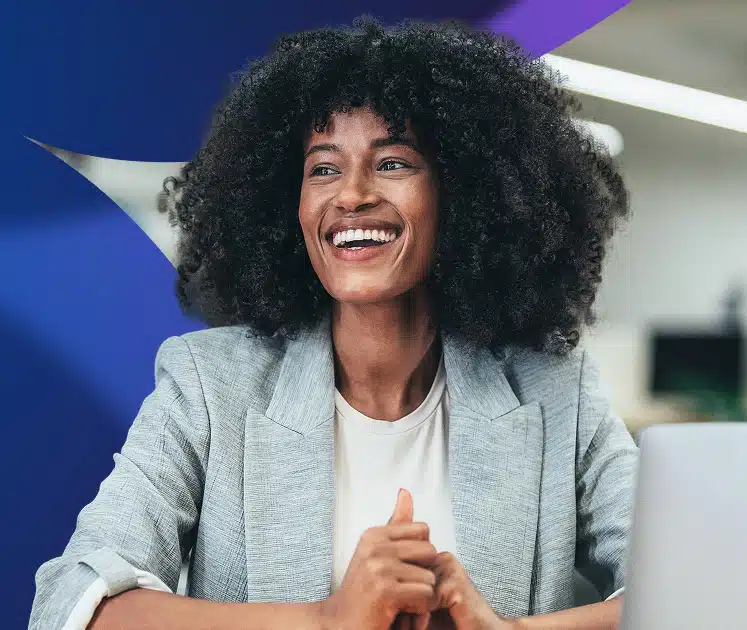 Female employee in business casual clothes sitting at her desk and smiling